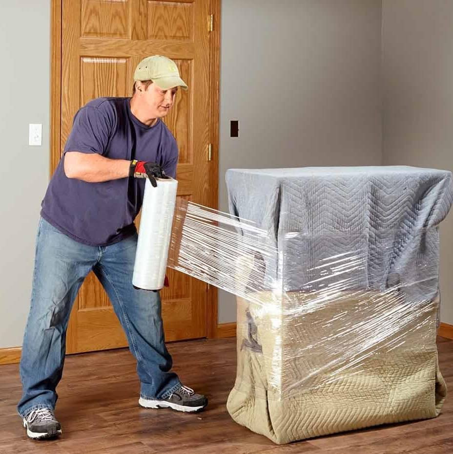 A person wrapping a piece of furniture in plastic